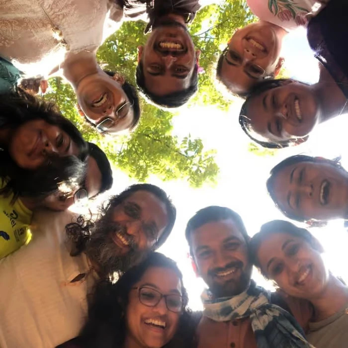 Purnam community members smiling in a circle under a tree